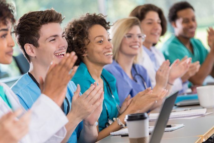 Diverse group of medical student applaud professor